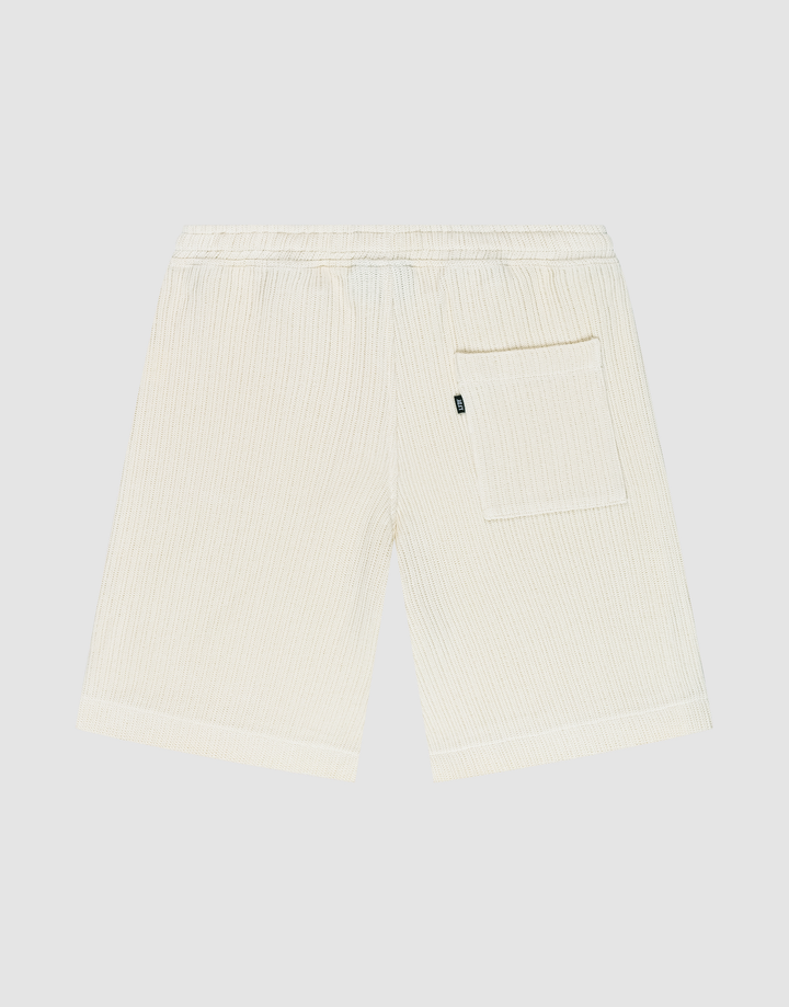Back view of Basic Knit Shorts by LIVE FAST DIE YOUNG in cream, featuring subtle vertical stripes, elastic waistband, and a single right patch pocket. The shorts are displayed flat on a plain light background.
