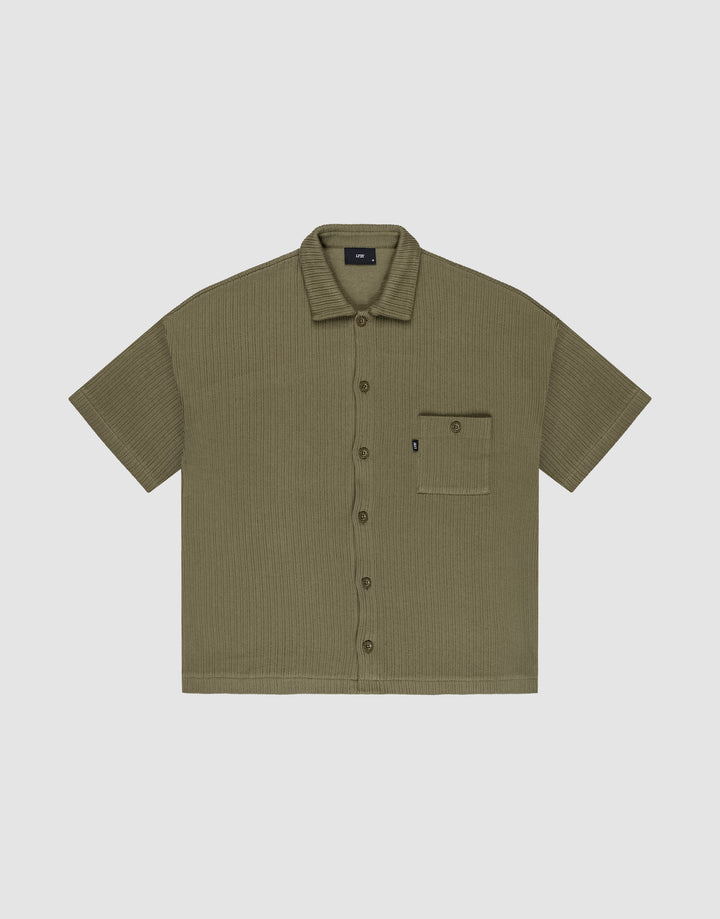 Olive green Basic Knit Shirt by LIVE FAST DIE YOUNG, oversize fit with short sleeves, textured fabric, and a single left chest pocket with a small black tag; shirt is laid flat on a light background. | plain