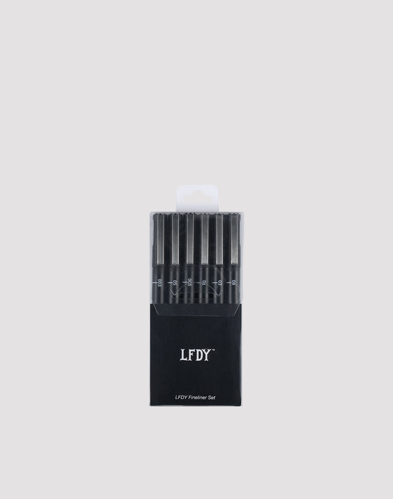 A black box labeled LIVE FAST DIE YOUNG LFDY Fineliner Set holds six wasserfest black fineliner pens with varying line widths, arranged vertically cap-up