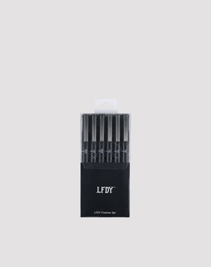 A black box labeled LIVE FAST DIE YOUNG LFDY Fineliner Set holds six wasserfest black fineliner pens with varying line widths, arranged vertically cap-up against a plain light gray background.