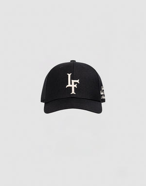 The LF Snapback by LIVE FAST DIE YOUNG is a black cotton baseball cap with white LF logo embroidery on the front and a snap closure, shown against a plain light gray background.