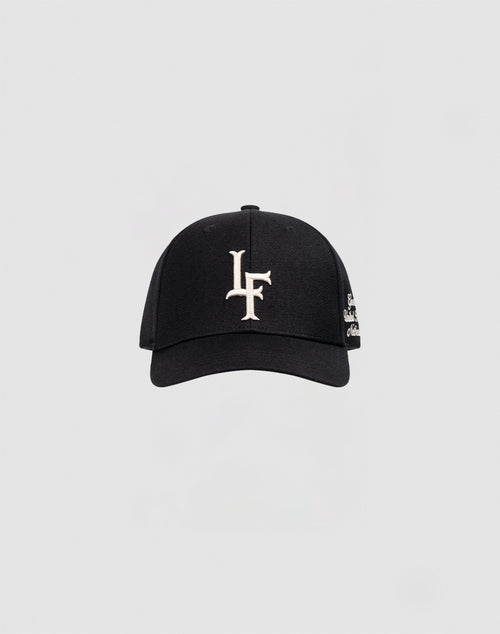 The LF Snapback by LIVE FAST DIE YOUNG is a black cotton baseball cap with white LF logo embroidery on the front and a snap closure, shown against a plain light gray background.