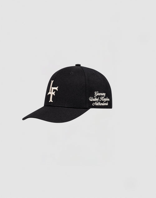 The LF Snapback by LIVE FAST DIE YOUNG is a black Baumwolle cap with a white LF logo stitch on the front, Germany/UK/Netherlands script on the side, and classic Snapverschluss. Shown against a plain light gray background.