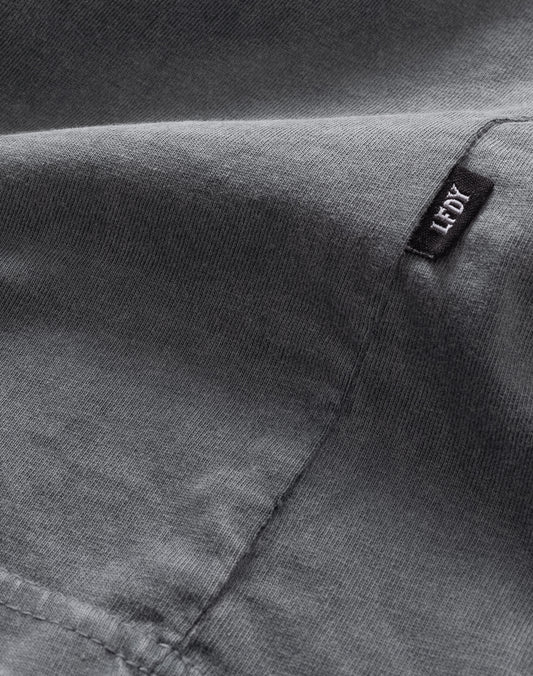Close-up of a gray Basic Light Tee by LIVE FAST DIE YOUNG, featuring visible stitching, a small black FLOY tag in white lettering, 100% Baumwolle construction, and an Oversize Fit for extra comfort.