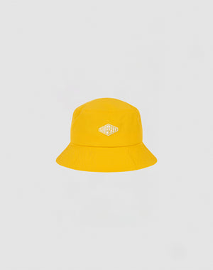 A bright yellow Nylon Bucket Hat from LIVE FAST DIE YOUNG features a small white and gold STAYCASS patch on the front. The hat is centered against a plain light gray background.