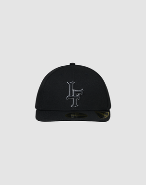 A black LFDY X NEW ERA 59FIFTY Low Profile fitted cap by LIVE FAST DIE YOUNG, featuring a flat brim and white LF initials embroidered on the front, displayed against a plain gray background.