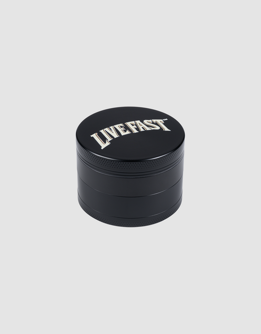 The LIVE FAST DIE YOUNG Live Fast Grinder is a schwarz, round 55 mm aluminium grinder with "LIVE FAST" in bold white text on the lid, shown against a plain light gray background.| plain 