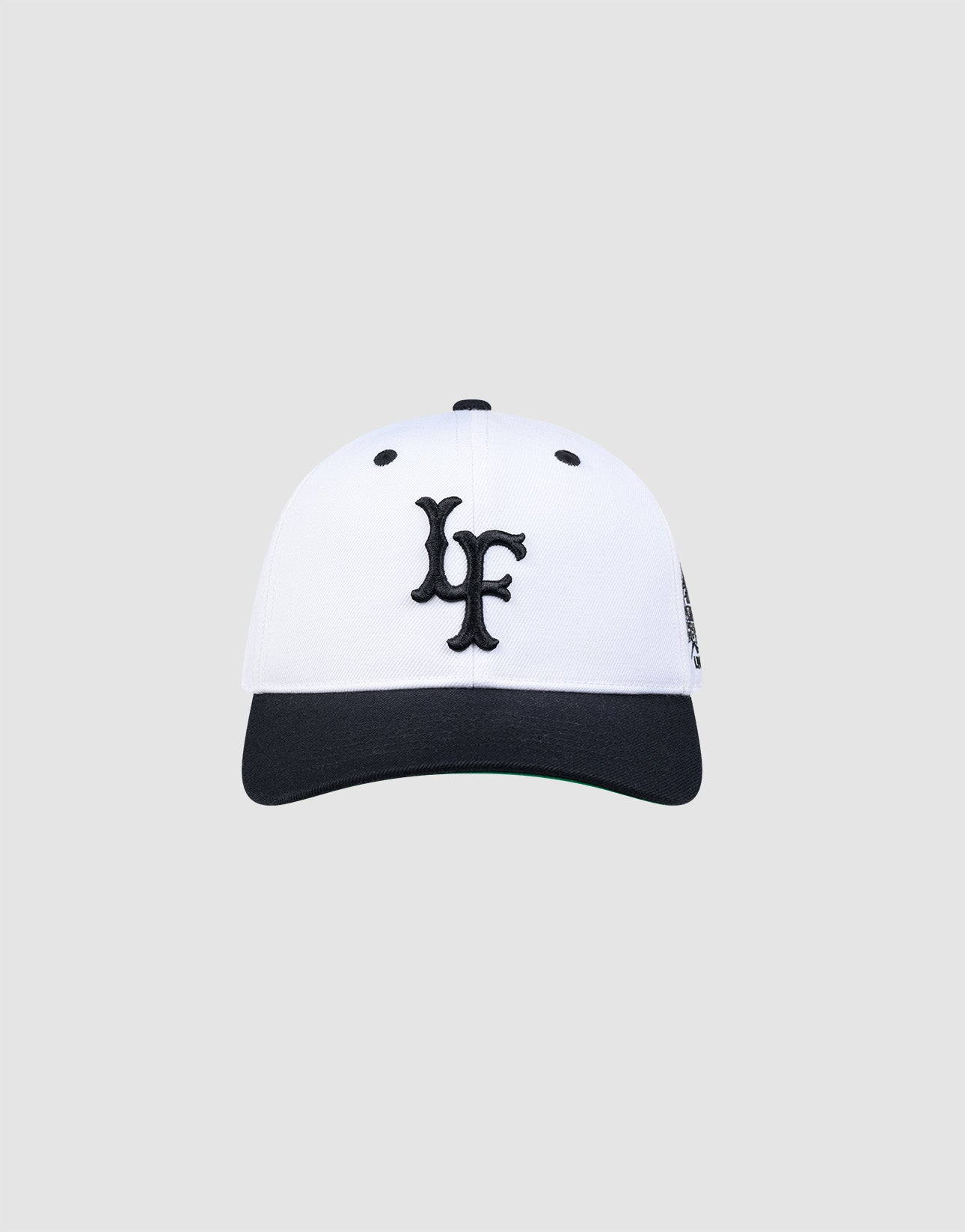 The LFDY Snapback by LIVE FAST DIE YOUNG features a white crown, black brim, black embroidered LF logo on the front, and a classic green underbrim, shown against a plain light grey background.