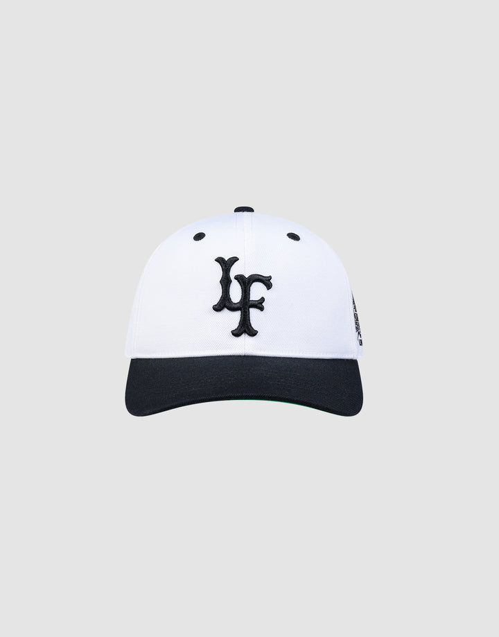 The LFDY Snapback by LIVE FAST DIE YOUNG features a white crown, black brim, black embroidered LF logo on the front, and a classic green underbrim, shown against a plain light grey background.