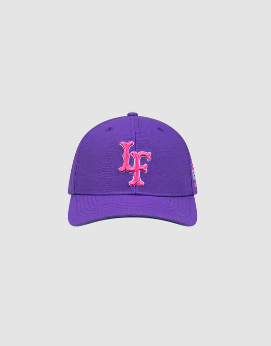 The LFDY Snapback by LIVE FAST DIE YOUNG is a purple cap with a pink LF logo, green underside of the brim, curved visor, and top button, shown on a plain light background.