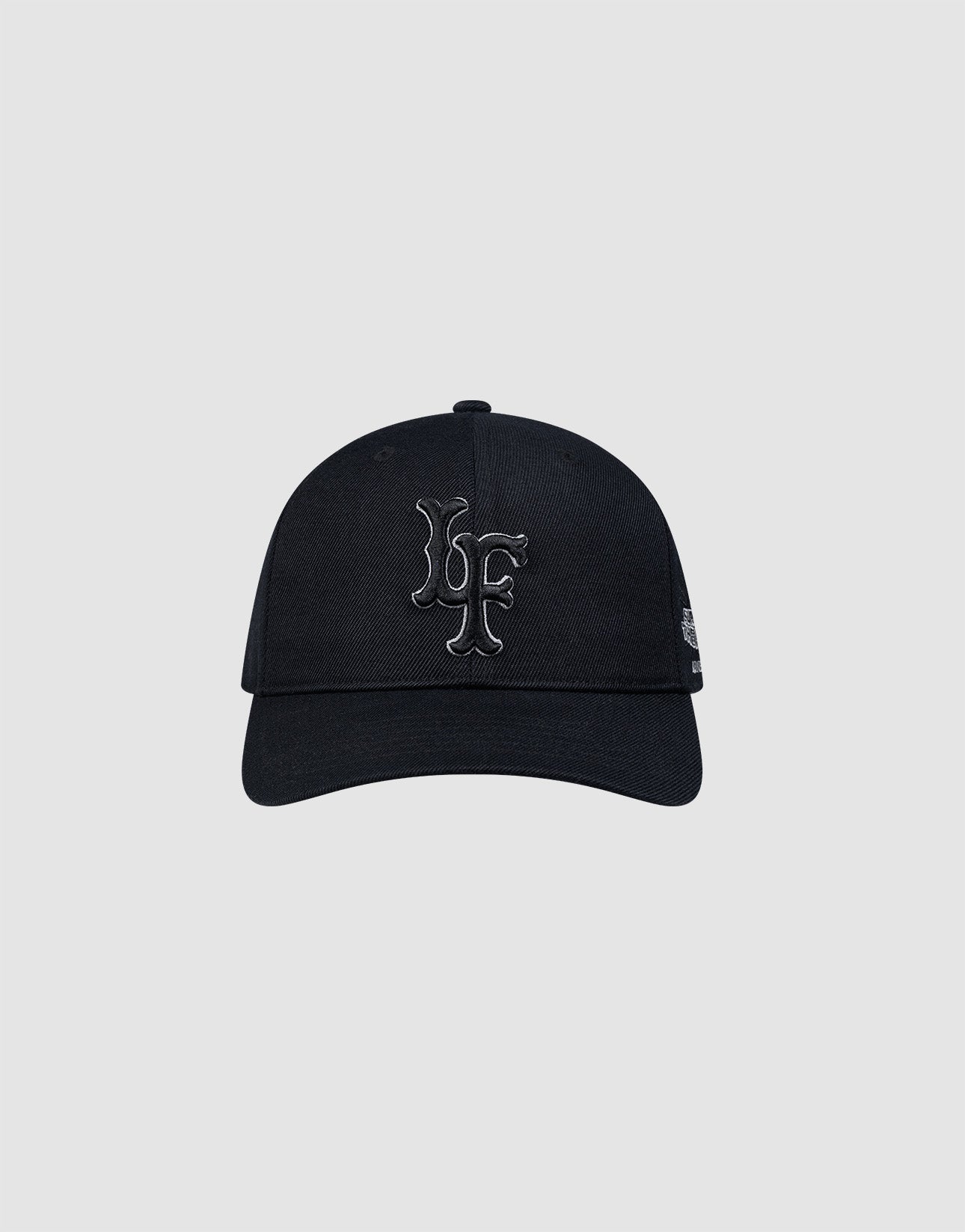 The LFDY Snapback by LIVE FAST DIE YOUNG is a black cap with a curved brim and grey underside, featuring large raised black LF initials on the front, a small white Multi-Logo-Stick on the left, and a practical snap closure.
