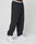 A person wears the LIVE FAST DIE YOUNG Basic Loose Jogger—black sweatpants with an elastik-bund and logo print waistband—paired with white sneakers, set against a plain light grey background.