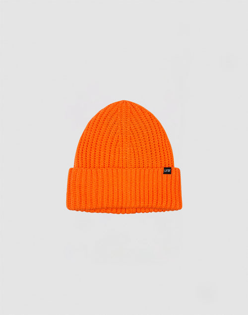 The Rib Knit Beanie by LIVE FAST DIE YOUNG is bright orange, made from soft Polyacryl, and features a folded cuff with a small black rectangular tag. Its shown against a plain light gray background.