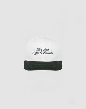 The LIVE FAST DIE YOUNG Live Fast Coffee Cap is a white, one size cap made from 100% Baumwolle with Live Fast Coffee & Cigarettes embroidered in dark green on the front, inspired by the LFDY Berlin Café and shown on a plain light gray background.