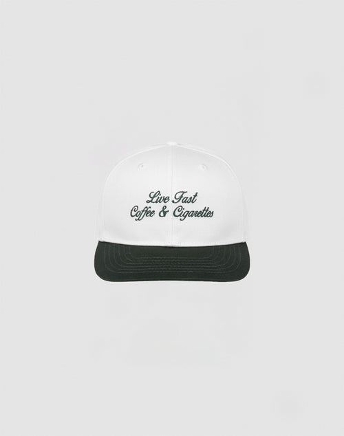 The LIVE FAST DIE YOUNG Live Fast Coffee Cap is a white, one size cap made from 100% Baumwolle with Live Fast Coffee & Cigarettes embroidered in dark green on the front, inspired by the LFDY Berlin Café and shown on a plain light gray background.