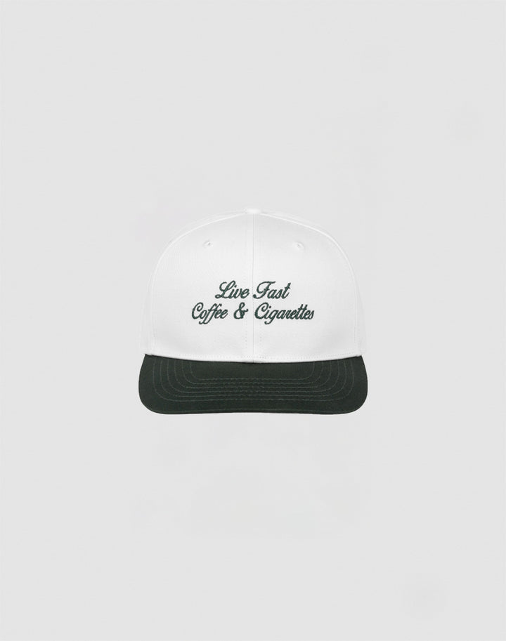 The LIVE FAST DIE YOUNG Live Fast Coffee Cap is a white, one size cap made from 100% Baumwolle with Live Fast Coffee & Cigarettes embroidered in dark green on the front, inspired by the LFDY Berlin Café and shown on a plain light gray background.