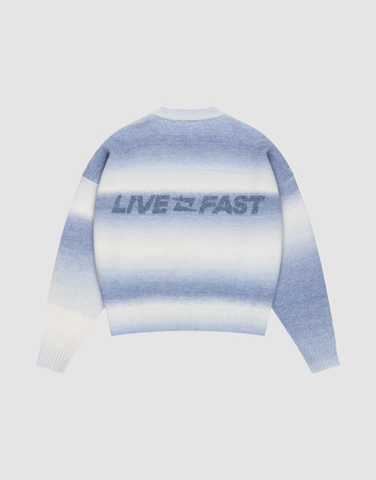 The Live Fast Boucle Sweater by LIVE FAST DIE YOUNG features a blue and white gradient, an oversize fit, and bold "LIVE FAST" lettering across the back, shown on a plain light gray background.