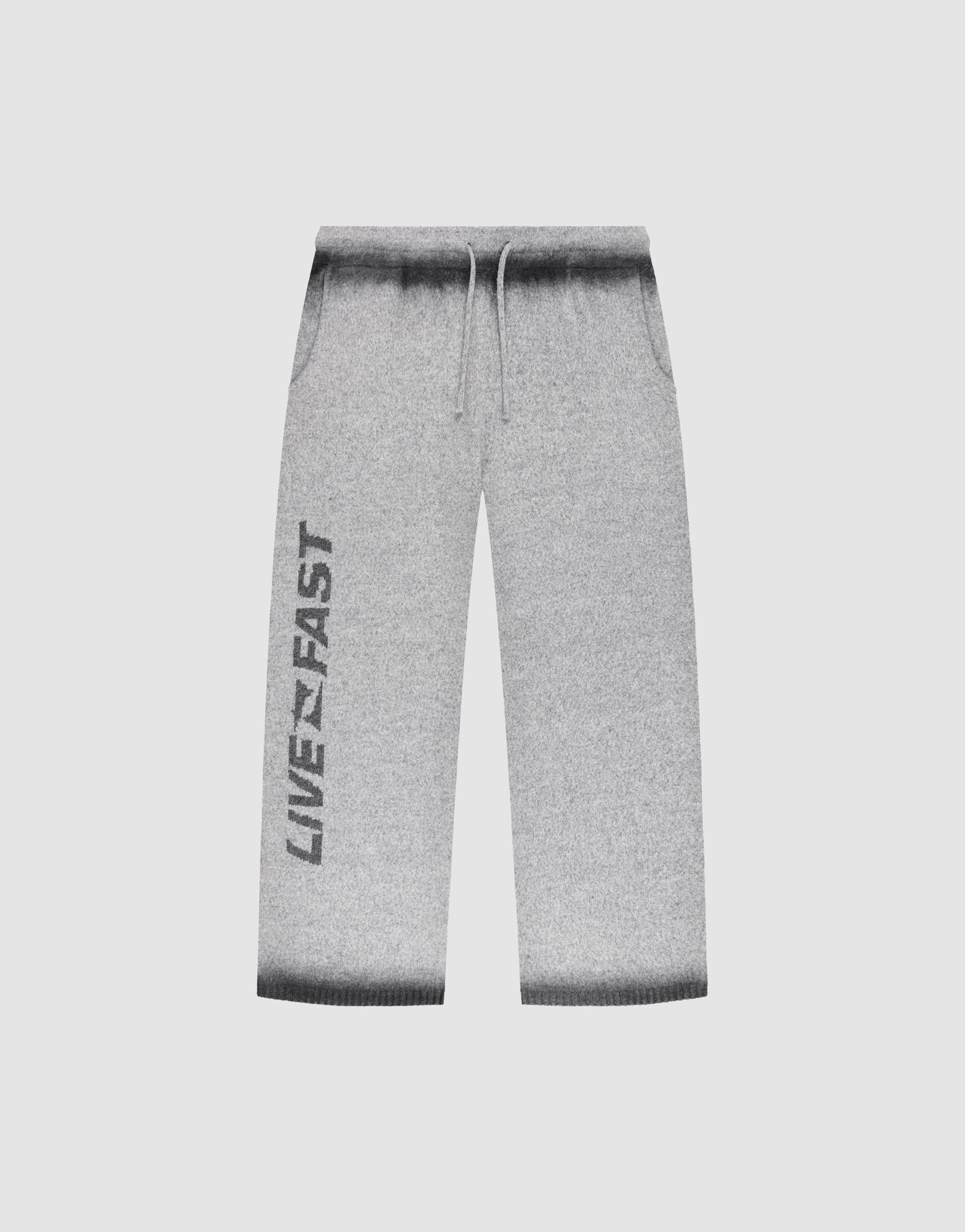 LIVE FAST DIE YOUNG’s Live Fast Boucle Pants: light gray, wide fit with straight leg, dark gray gradient waistband/cuffs, drawstring elastic waist, side pockets, and bold black LIVE FAST print down the left leg.