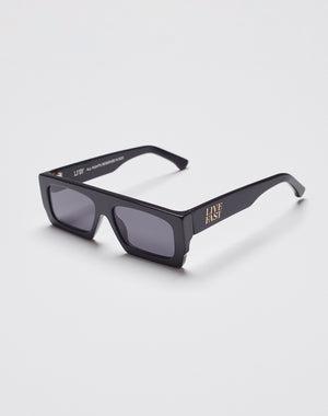 Live Fast Shades by LIVE FAST DIE YOUNG are black rectangular sunglasses with thick, polished LAES acetate frames, dark lenses with 400 UV protection, and “LIVE FAST” in gold on the side, shown on a plain white background.