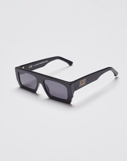 Live Fast Shades by LIVE FAST DIE YOUNG are black rectangular sunglasses with thick, polished LAES acetate frames, dark lenses with 400 UV protection, and “LIVE FAST” in gold on the side, shown on a plain white background.