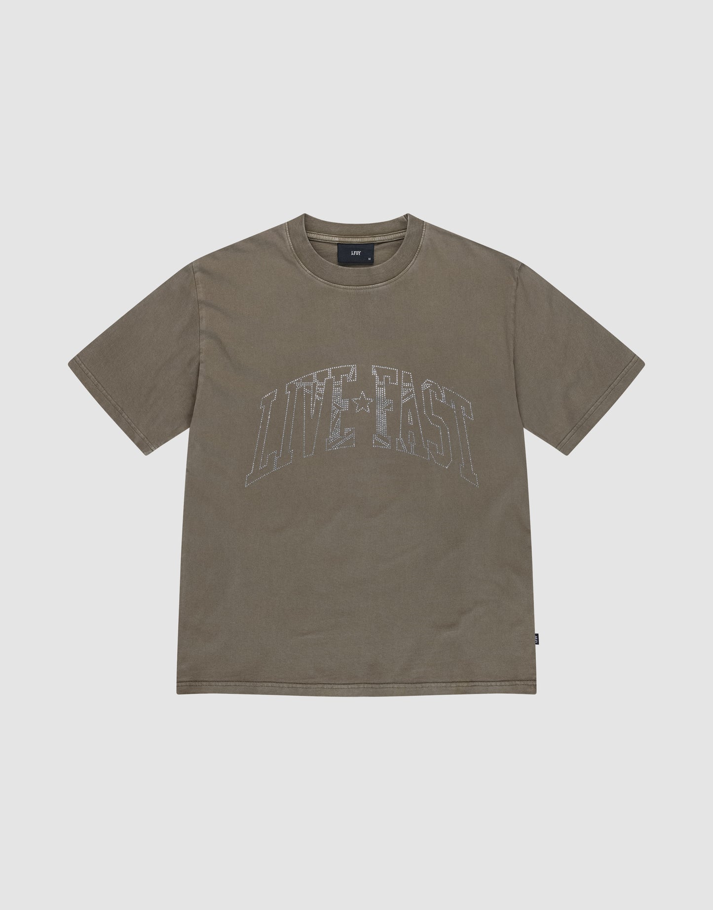 The Live Fast Rhinestone Tee by LIVE FAST DIE YOUNG is a short-sleeved, olive green shirt with vintage wash and bold, distressed "LIVE FAST" lettering in white across the chest, set against a solid light gray background.