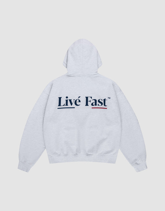 The Live Fast Paris Hooded by LIVE FAST DIE YOUNG is an oversized, light gray cotton hoodie with a bold "Livé Fast" black backprint and red underline, displayed flat on a plain white background. | plain