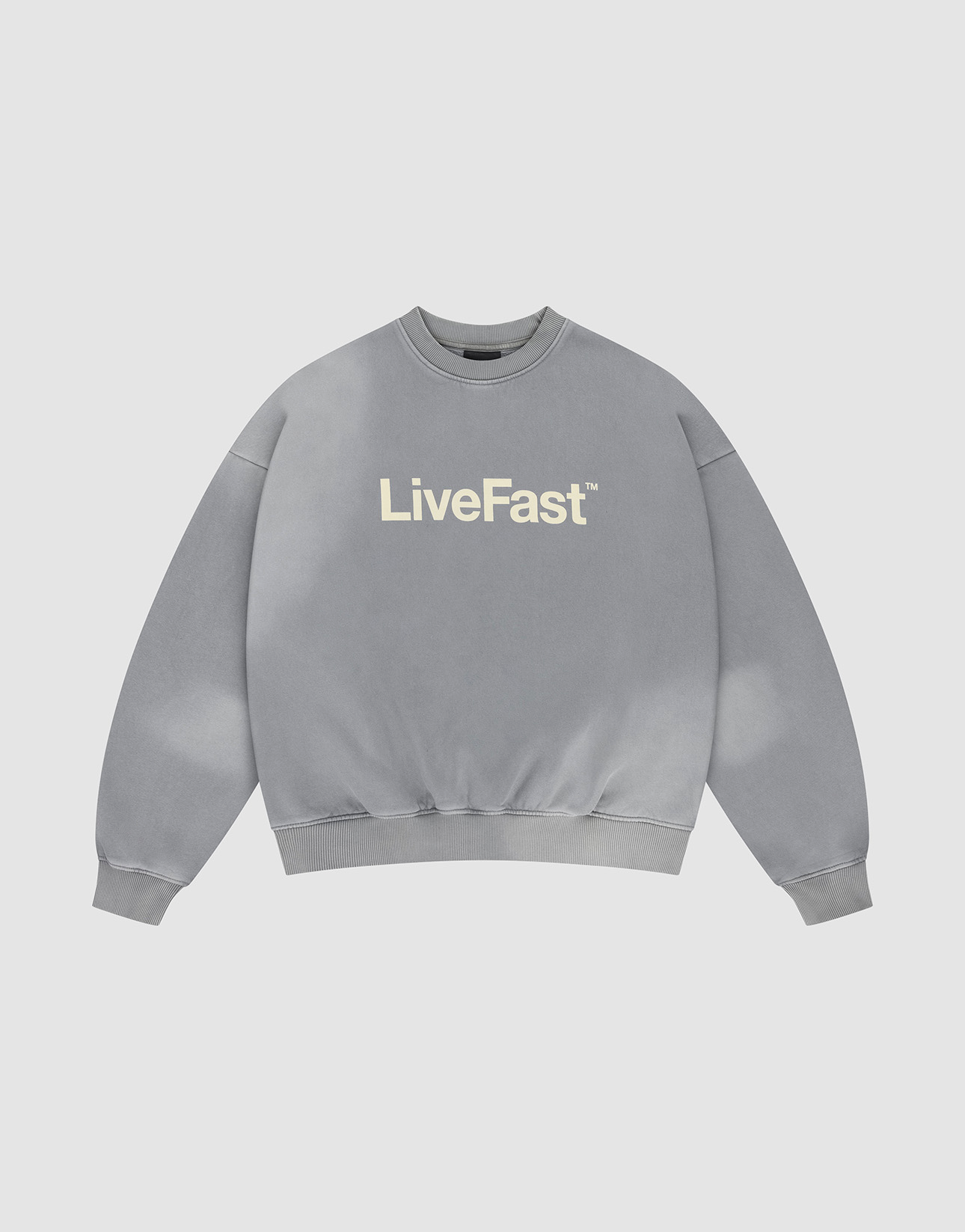 The Basic LiveFast Sweater by LIVE FAST DIE YOUNG is a gray, oversized crewneck with “LiveFast” in bold white on the chest and a subtle handgefertigter Fade-Effekt, shown laid flat on a plain light background.