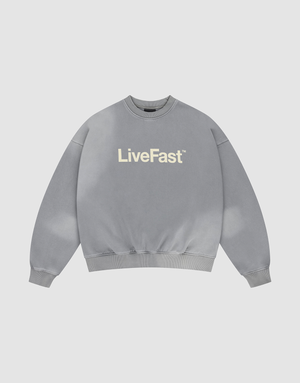 The Basic LiveFast Sweater by LIVE FAST DIE YOUNG is a gray, oversized crewneck with “LiveFast” in bold white on the chest and a subtle handgefertigter Fade-Effekt, shown laid flat on a plain light background. | plain