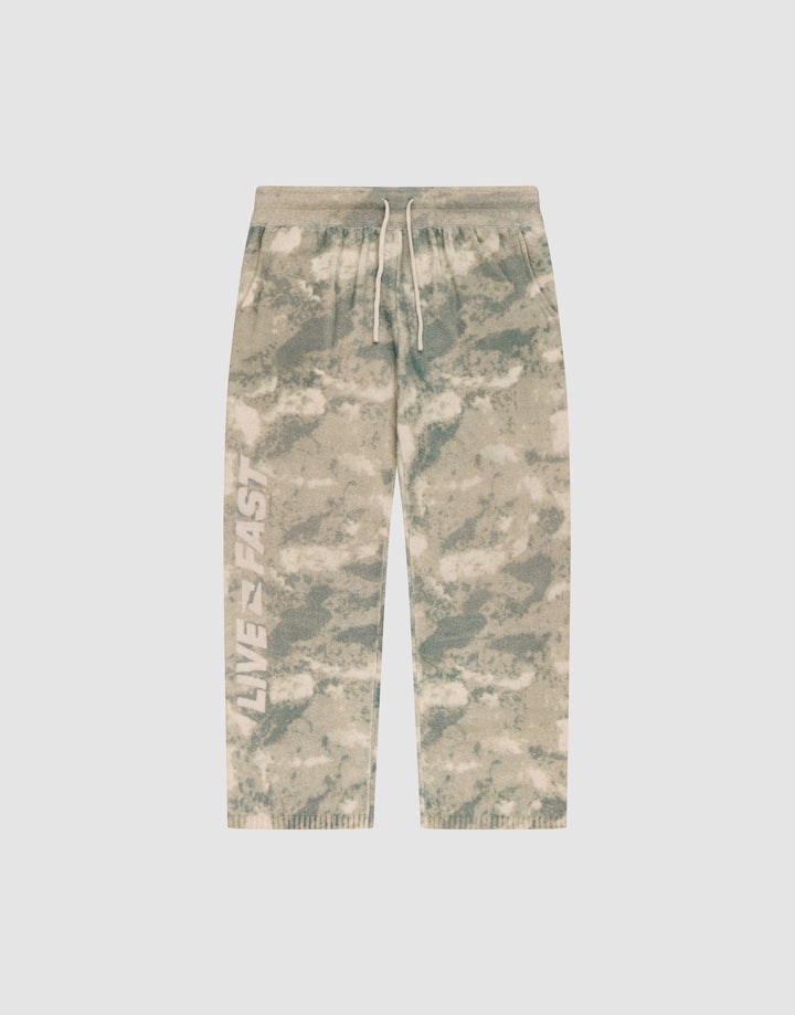 The LIVE FAST DIE YOUNG Live Fast Boucle Pants feature a beige and green tie-dye design, white drawstring, elastic waistband, "LIVE FAST" on the left leg, relaxed wide fit with straight leg and ribbed cuffs for comfort. | plain