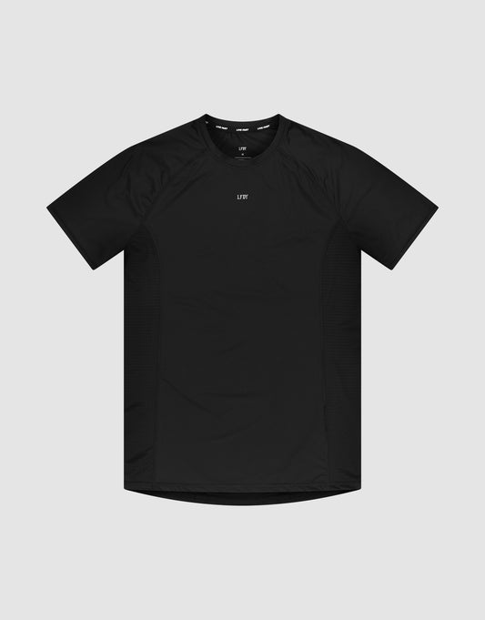 The LFDY Performance Slim Tee by LIVE FAST DIE YOUNG is a black slim-fit, short-sleeve athletic t-shirt with a crew neck and a small white reflective logo print at the center chest, shown against a light gray background. | plain