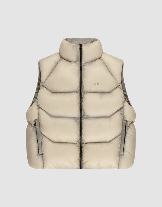 The Live Fast Puffer Vest by LIVE FAST DIE YOUNG features a beige color, high collar, black front zipper, two zippered side pockets, and an oversize fit, shown against a plain light gray background. | plain