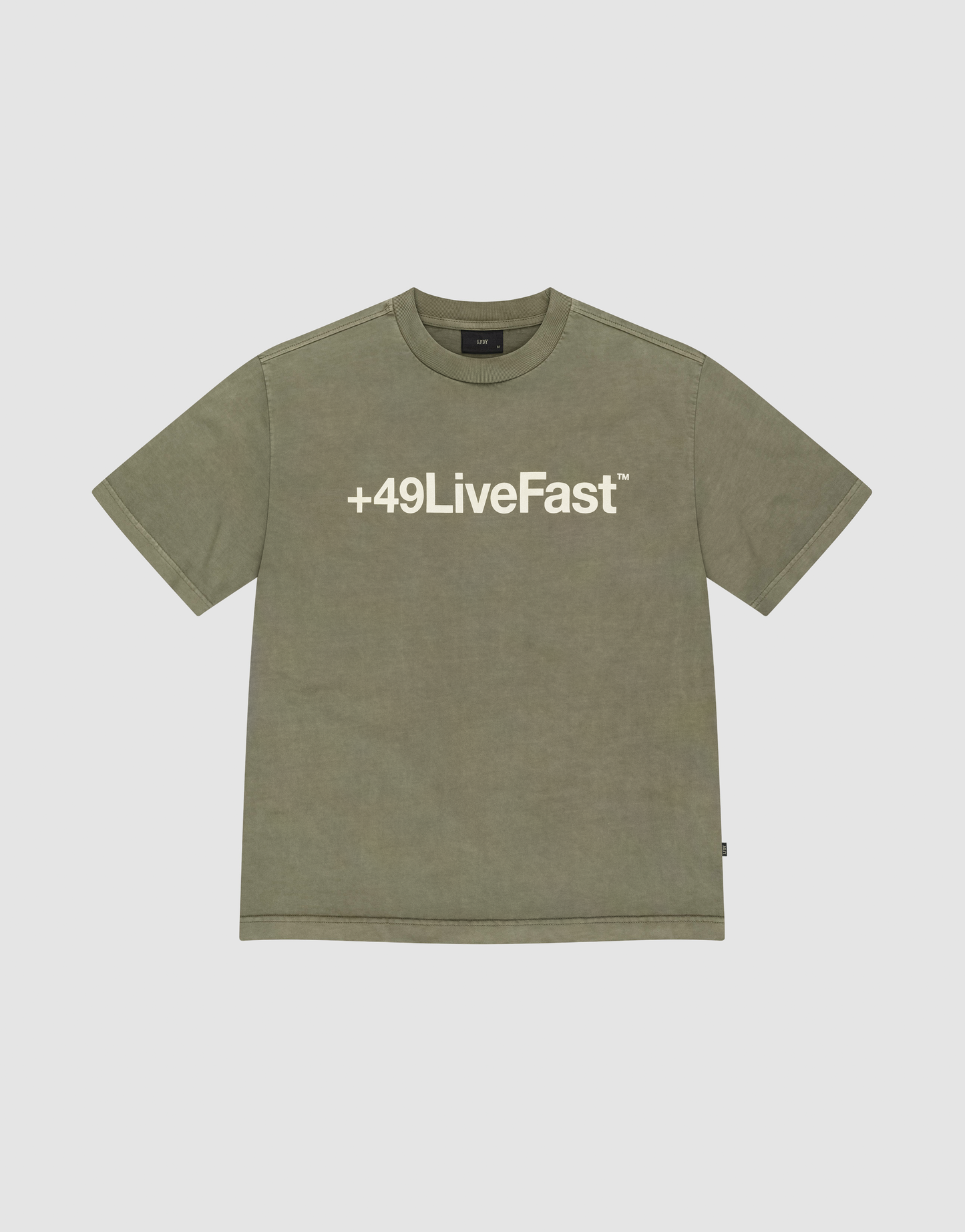 The Basic +49 Tee by LIVE FAST DIE YOUNG is an olive green, oversize short-sleeve T-shirt with a bold white +49LiveFast™ front print, made from 100% Baumwolle and shown on a plain light grey background.