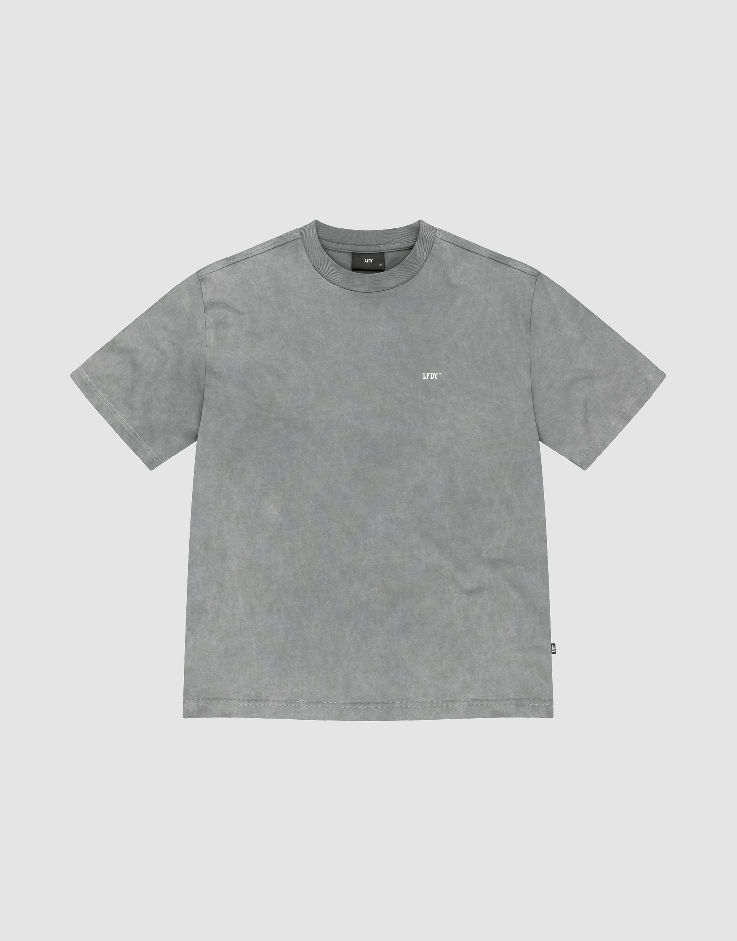 The Basic Trademark Tee by LIVE FAST DIE YOUNG is a gray, short-sleeved crew neck shirt with a small white logo on the upper left chest, made from 100% Baumwolle and displayed flat on a light gray background. | plain