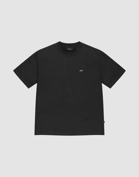 The Basic Trademark Tee by LIVE FAST DIE YOUNG is an Oversize Fit black short-sleeve shirt with a small white LIFE logo on the left chest, made from 100% Baumwolle and shown on a light gray background.