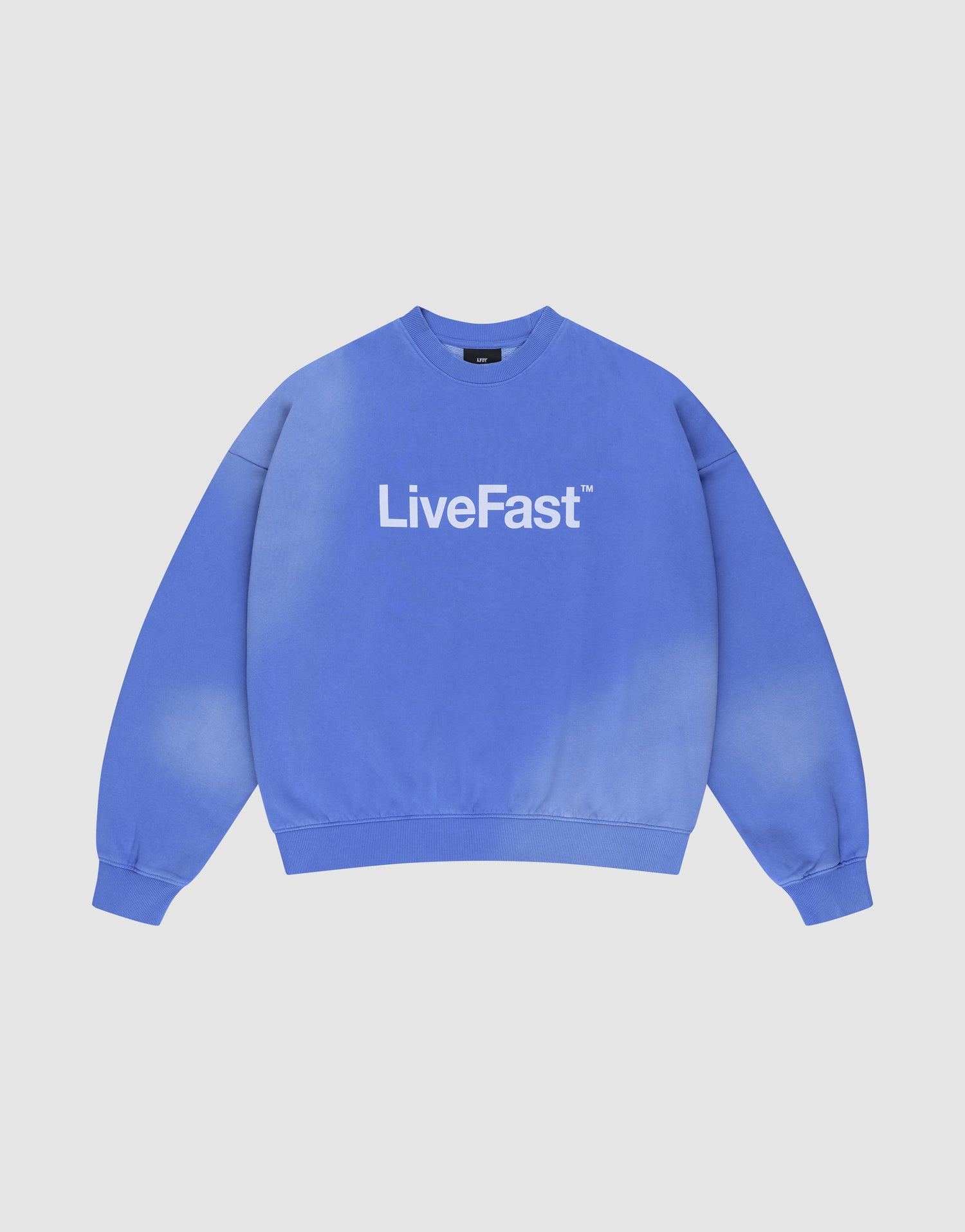 The Basic LiveFast Sweater by LIVE FAST DIE YOUNG is a blue, oversized crewneck with bold white "LiveFast" lettering and a handgefertigter Fade-Effekt, shown laid flat on a white background. | plain