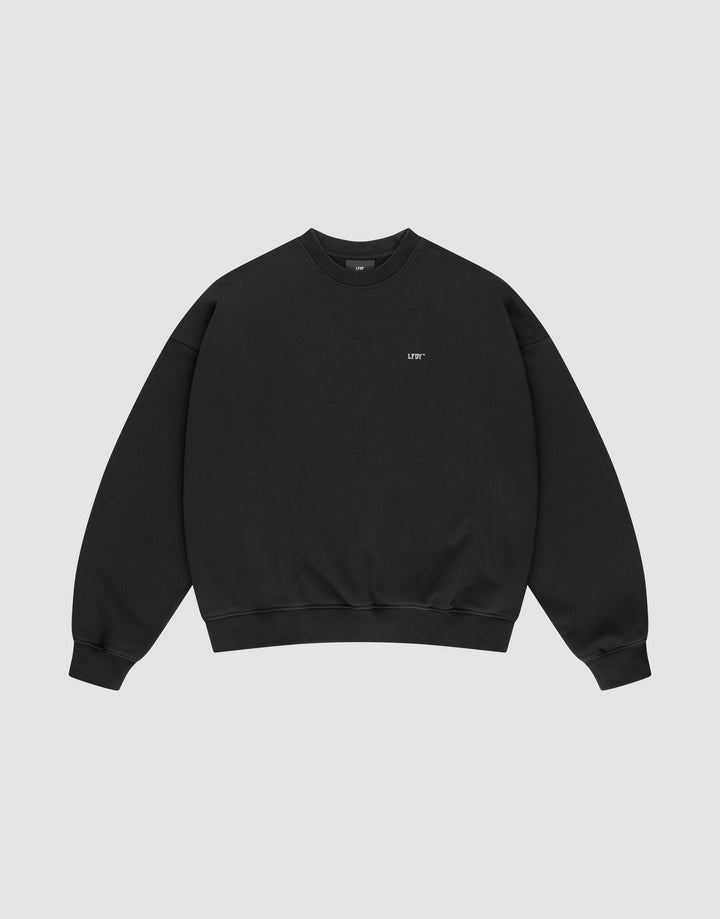 The Basic Evidence Sweater by LIVE FAST DIE YOUNG is a black crewneck with long sleeves, ribbed cuffs, and soft Baumwolle-Polyester blend. Features small white "LIFE" text on the left chest, shown on a light gray background.