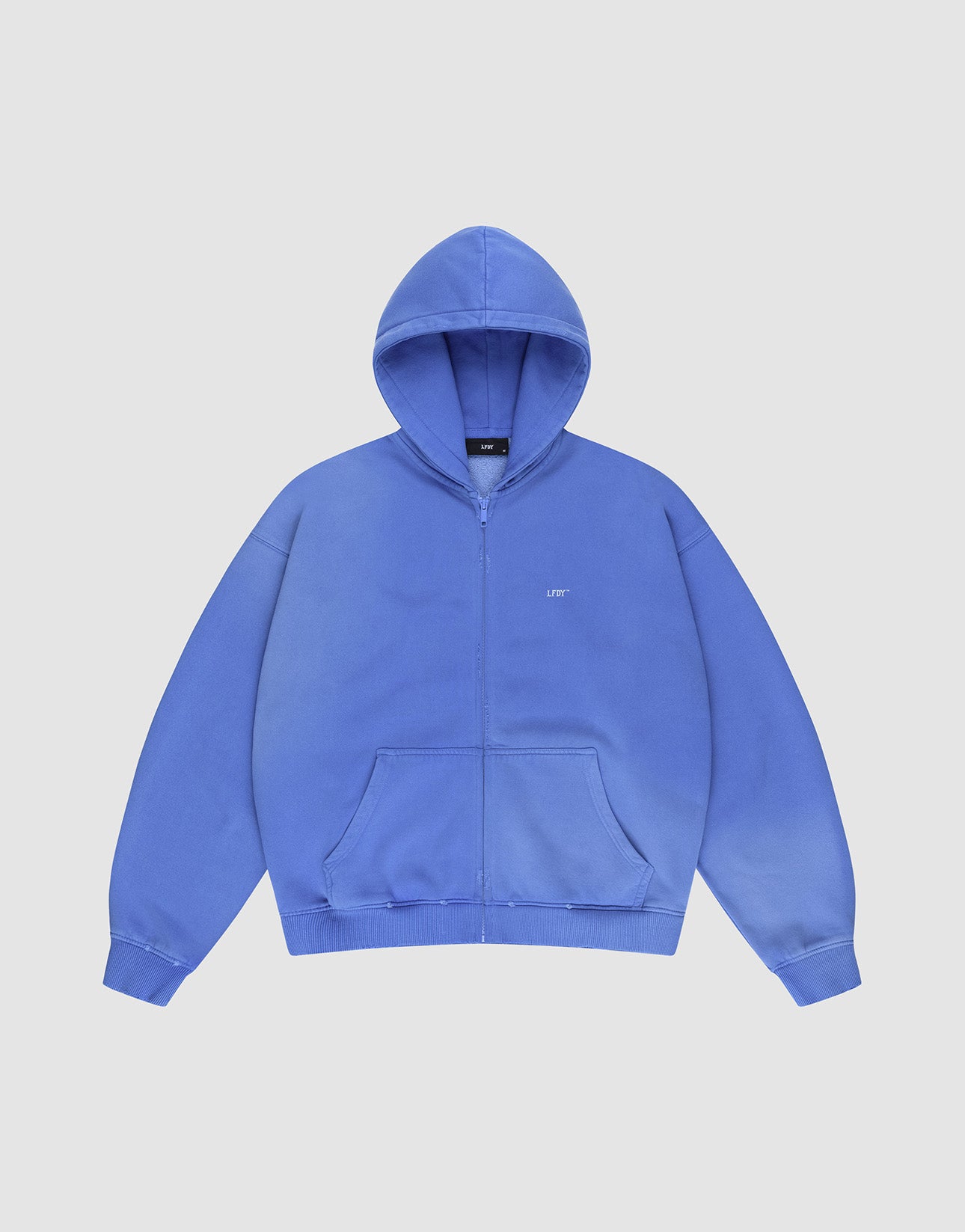 The LIVE FAST DIE YOUNG Basic Hooded Zip is a blue, oversized zip-up hoodie with a hood, front pockets, subtle LFTS text on the left chest, and a faded look, shown against a plain white background.