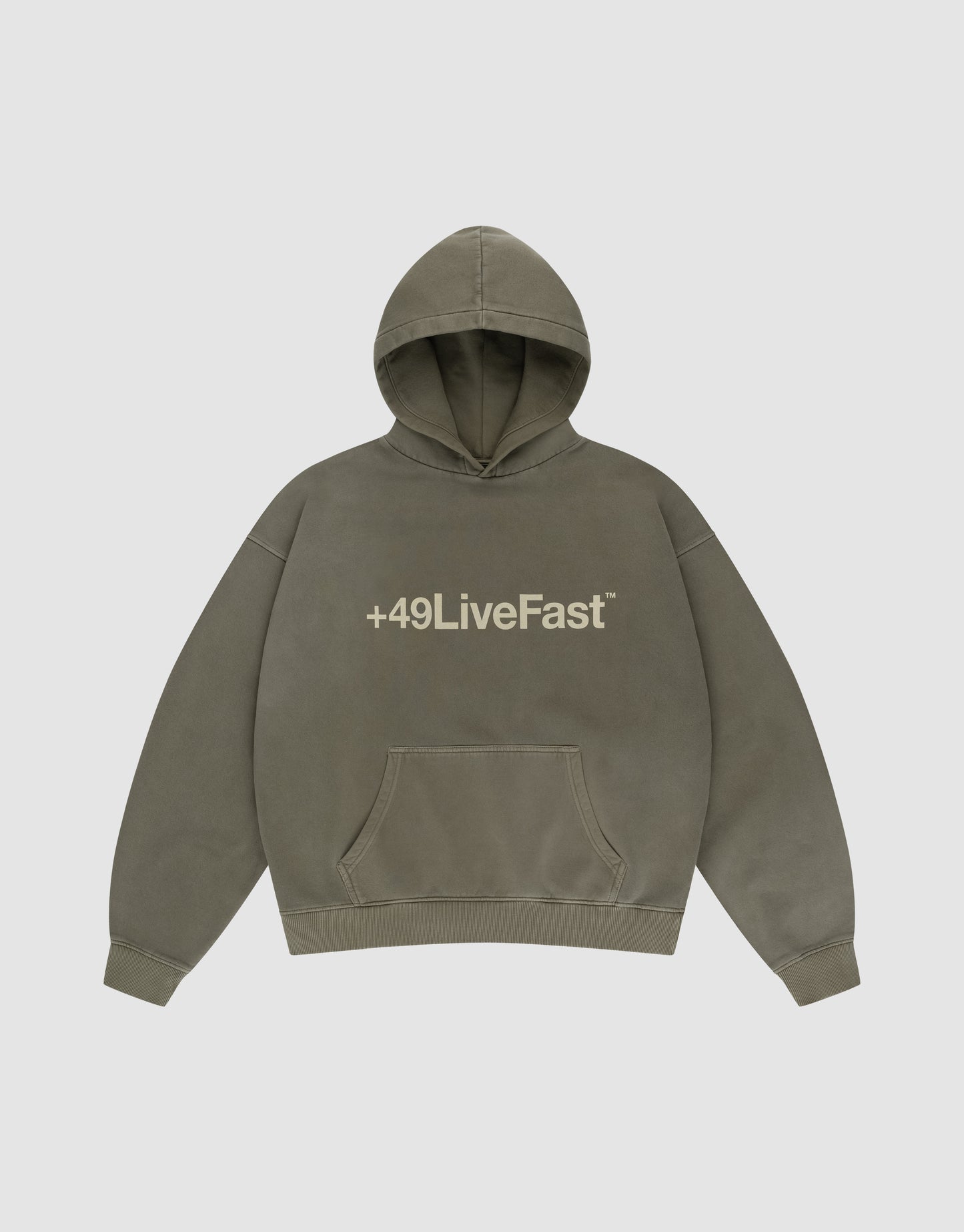 The Basic +49 Hooded by LIVE FAST DIE YOUNG is an olive green oversized sweatshirt with a handmade fade effect, beige “+49LiveFast™” print on the chest, a front pocket, and a plain light gray background.