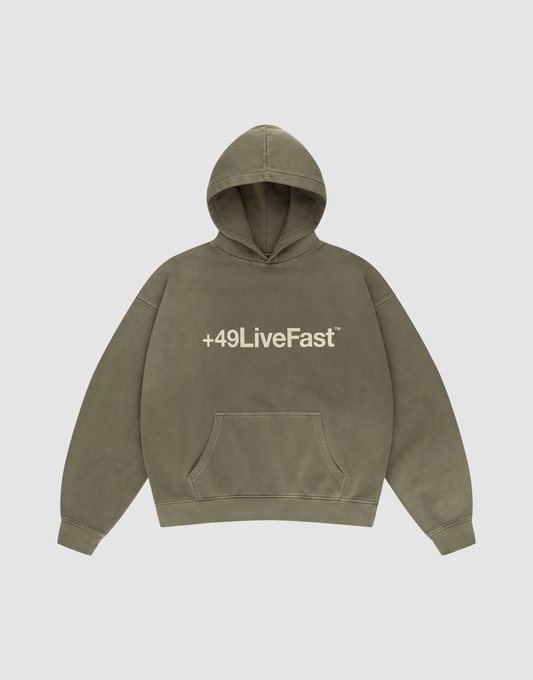 The Basic +49 Hooded by LIVE FAST DIE YOUNG is an olive green oversized sweatshirt with a front pocket, white +49LiveFast™ text on the chest, and a handgefertigter Fade-Effekt, shown on a plain light background. | plain