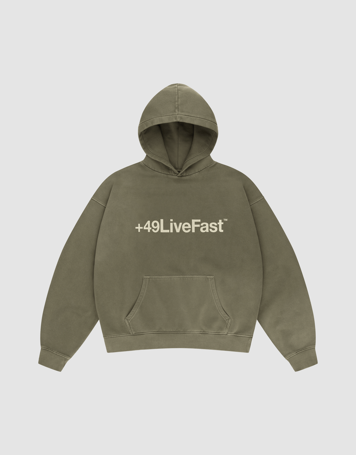 The Basic +49 Hooded by LIVE FAST DIE YOUNG is an olive green oversized sweatshirt with a front pocket, white +49LiveFast™ text on the chest, and a handgefertigter Fade-Effekt, shown on a plain light background. | plain