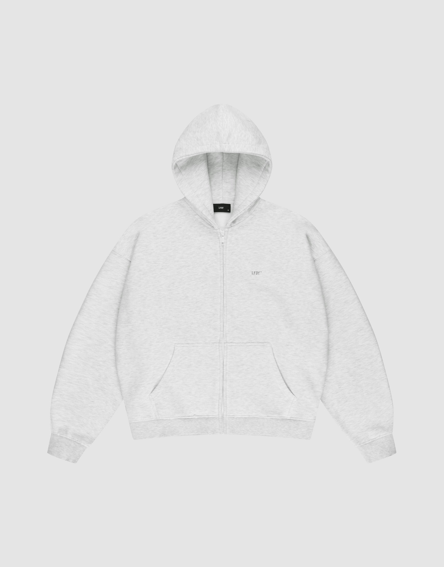 The LIVE FAST DIE YOUNG Basic Hooded Zip is a light gray zip-up hoodie with an oversize fit, front pockets, and a hood. It features subtle LFDY branding on the chest and is shown laid flat on a plain white background.