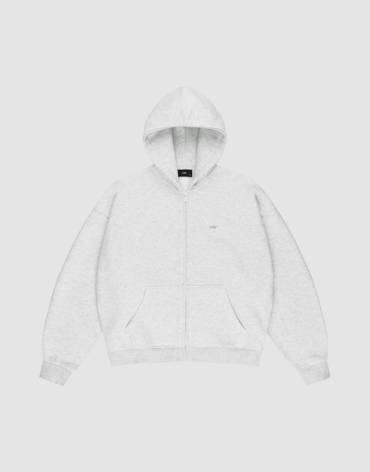 The LIVE FAST DIE YOUNG Basic Hooded Zip is a light gray zip-up hoodie with an oversize fit, front pockets, and a hood. It features subtle LFDY branding on the chest and is shown laid flat on a plain white background. | plain