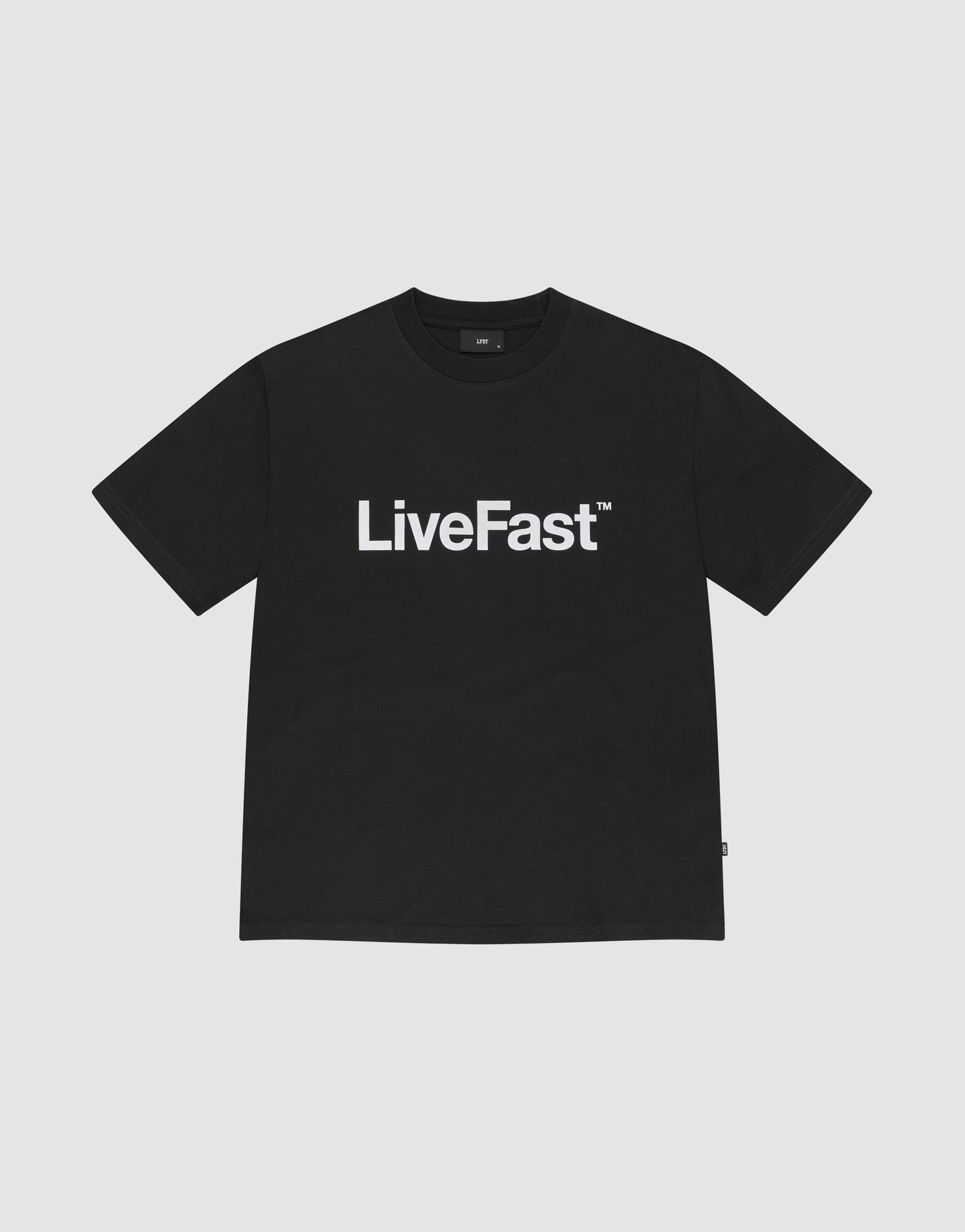 The Basic LiveFast Tee by LIVE FAST DIE YOUNG is a black regular fit T-shirt with a bold "LiveFast™" front print, made from 100% Baumwolle, shown on a plain light gray background.