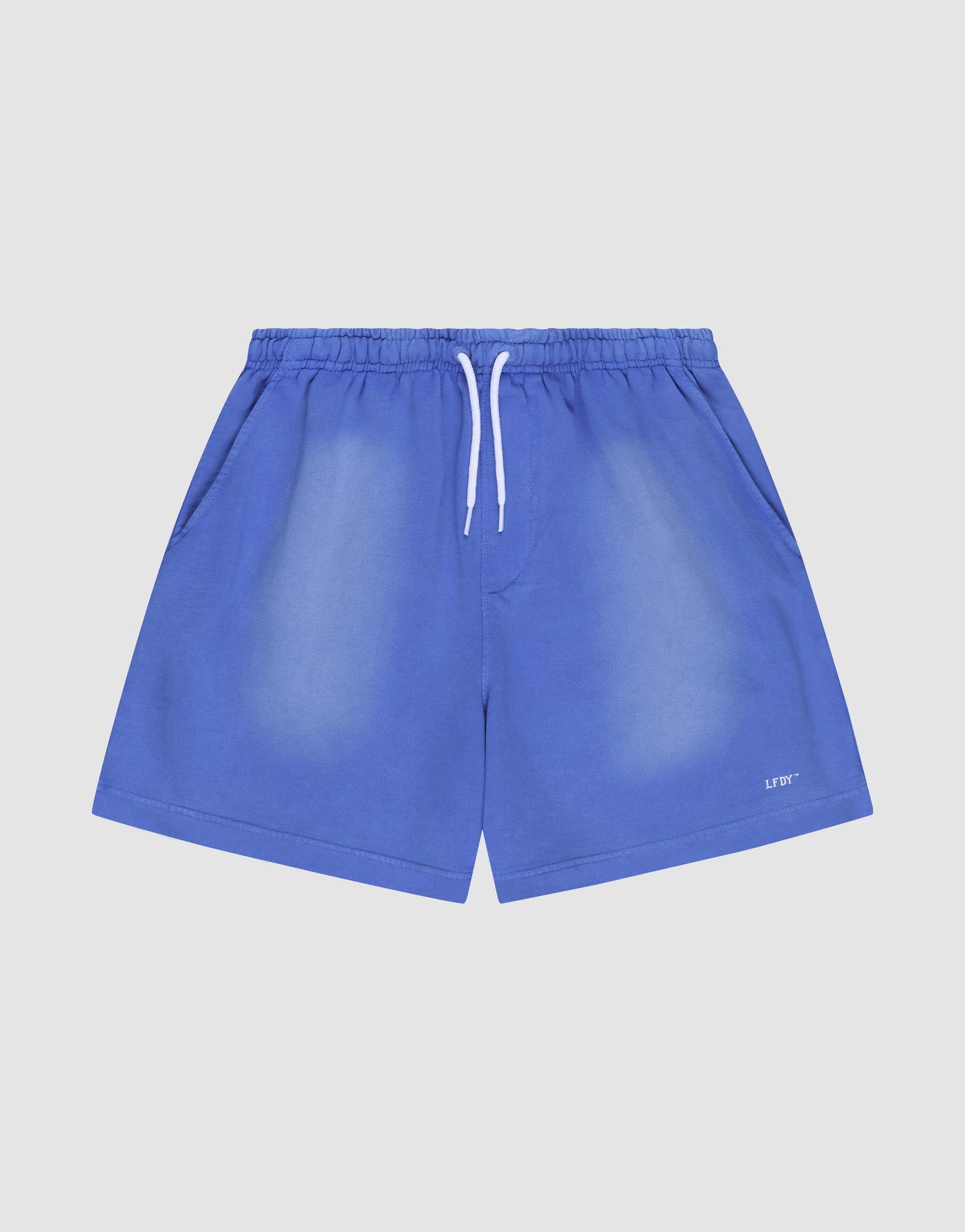 The LIVE FAST DIE YOUNG Basic Sweat Shorts in blue feature an elastic waistband, white drawstring, side pockets, and a small white logo print on the lower left leg, shown against a plain light background.