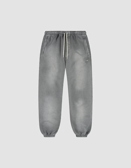 The LIVE FAST DIE YOUNG Basic Loose Jogger is a pair of gray washed sweatpants with a subtle fade effect, elastic waistband and white drawstring, side pockets, and elastic ankle cuffs, shown on a plain light background. | plain