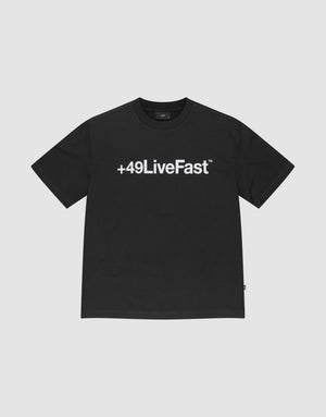 The Basic +49 Tee by LIVE FAST DIE YOUNG features a bold white +49LiveFast™ print across the chest, made from 100% cotton in an oversized fit, shown on a plain light grey background. | plain