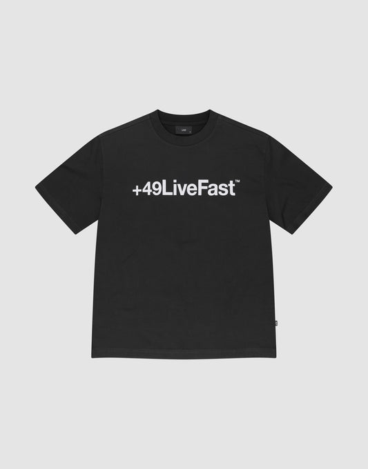 The Basic +49 Tee by LIVE FAST DIE YOUNG features a bold white +49LiveFast™ print across the chest, made from 100% cotton in an oversized fit, shown on a plain light grey background. | plain
