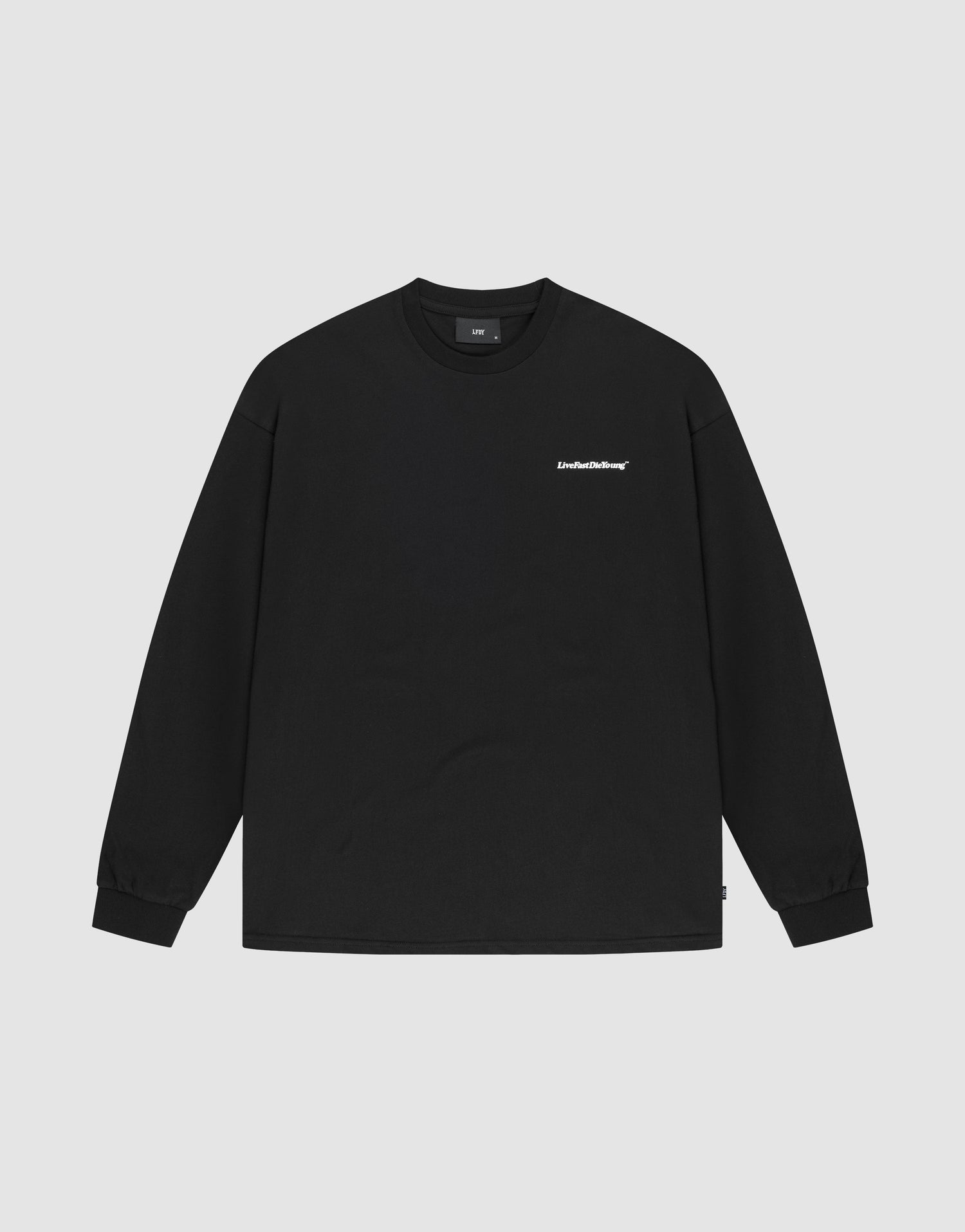 The LIVE FAST DIE YOUNG Basic Longsleeve is a plain black, crewneck long-sleeve shirt with a small white logo print on the left chest, made from 100% Baumwolle and shown laid flat on a light gray background. | plain