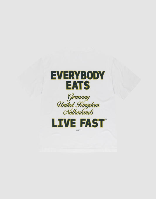 The Everybody Eats Tee by LIVE FAST DIE YOUNG is a white oversized cotton T-shirt with bold black and yellow front and back prints reading "EVERYBODY EAT$ Germany United Kingdom Netherlands LIVE FAST™," shown flat on a light gray background. | plain