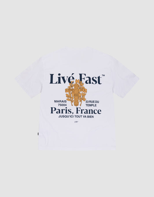 The LFDY Paris Tee by LIVE FAST DIE YOUNG is an oversized white shirt made from 100% cotton, with bold navy "Live Fast" front and back prints, orange graphics, and Paris—33 Rue Du Temple—Marais 75004 details. | plain
